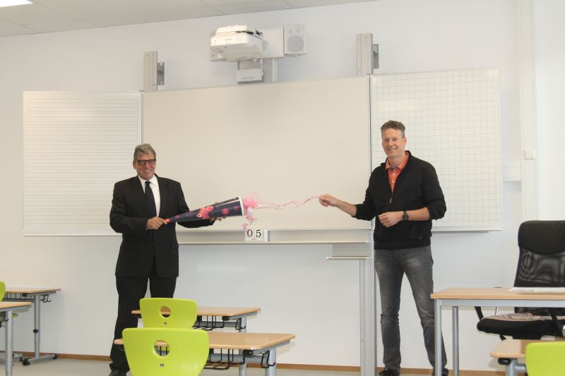 Zum ersten Schultag in der neuen Waldschule brachte Andree Stein (l.) eine Schultte gefllt mit Naschereien fr die Viertklssler und das Kollegium mit. Mit gebhrendem Abstand nahm Schulleiter Stefan Gleis das Geschenk entgegen. Foto: Pressedienst VG Montabaur