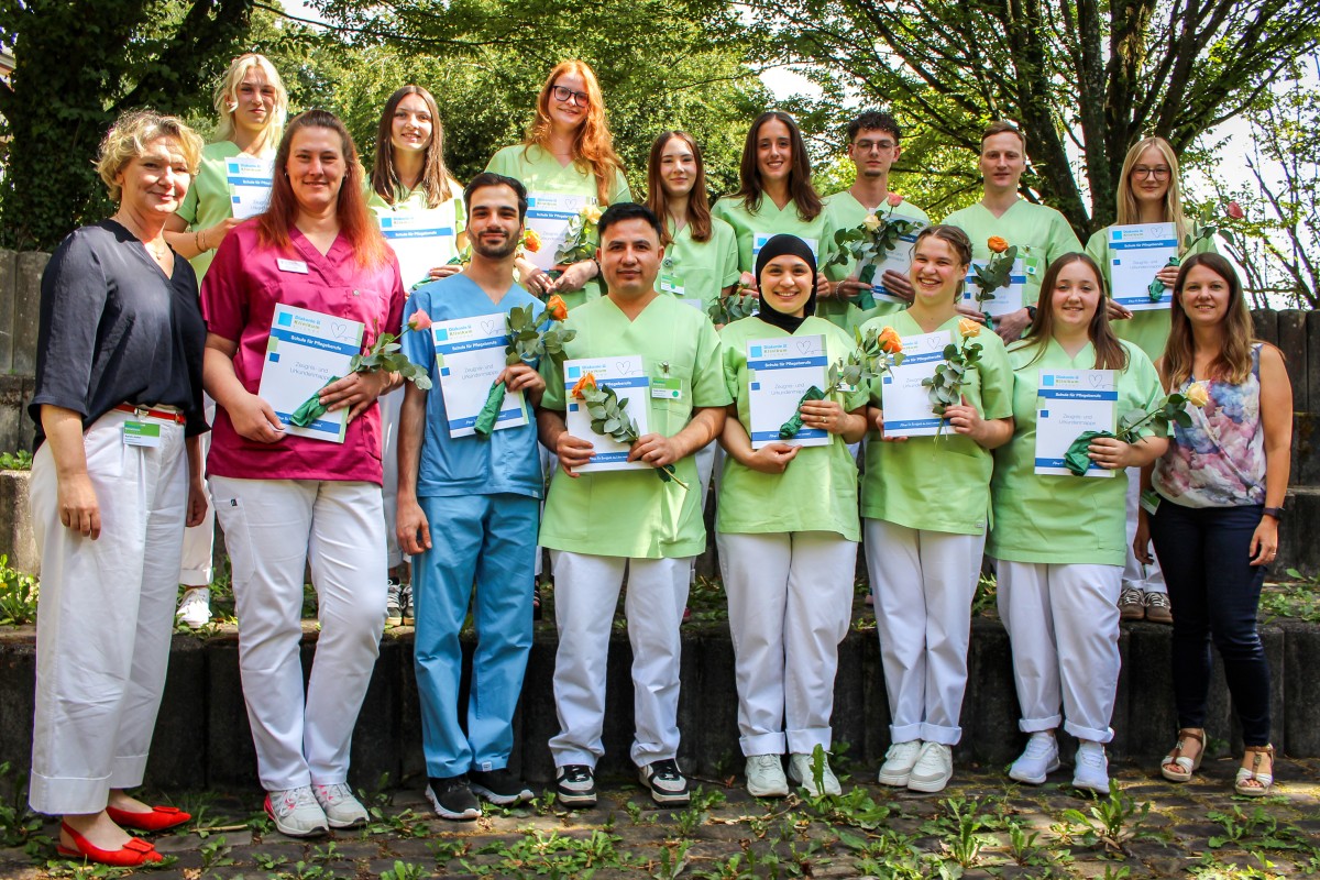Schulleiterin Karola Jockel (links) und Kursleiterin Lisa Friese (rechts) gratulierten den 14 Pflegefachfrauen und -m�nnern, die nach dreij�hriger Ausbildung an der Schule f�r Pflegeberufe in Kirchen nun ihr Examen in der Tasche haben. (Foto: Diakonie in S�dwestfalen)