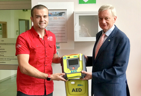 Der neue AED in der Verbandsgemeindeverwaltung Westerburg. Brgermeister Gerhard Loos (rechts) und Ren Schultheis, der Sachbearbeiter fr Arbeitssicherheit- und Gesundheitsschutz, nehmen das Gert der Firma Zoll entgegen und freuen sich darber, einen Beitrag zur Sicherheit und Gesundheit in Westerburg leisten zu knnen. (Verbandsgemeindeverwaltung Westerburg) 