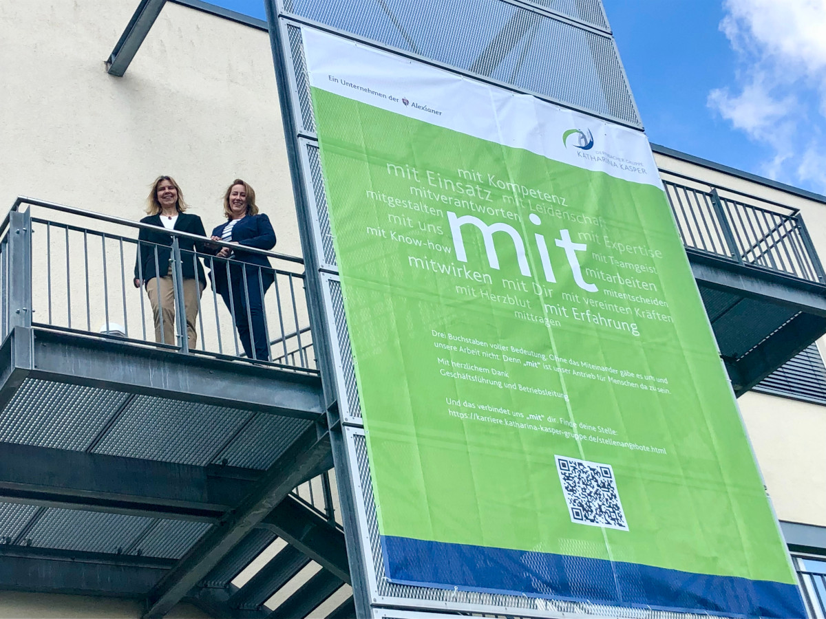 Kaufmnnische Direktorin Carmen Elschner (l.) und Pflegedirektorin Astrid Eisenberg stehen hinter der Botschaft auf dem groen Banner am Herz-Jesu-Krankenhaus. (Foto: DGKK)