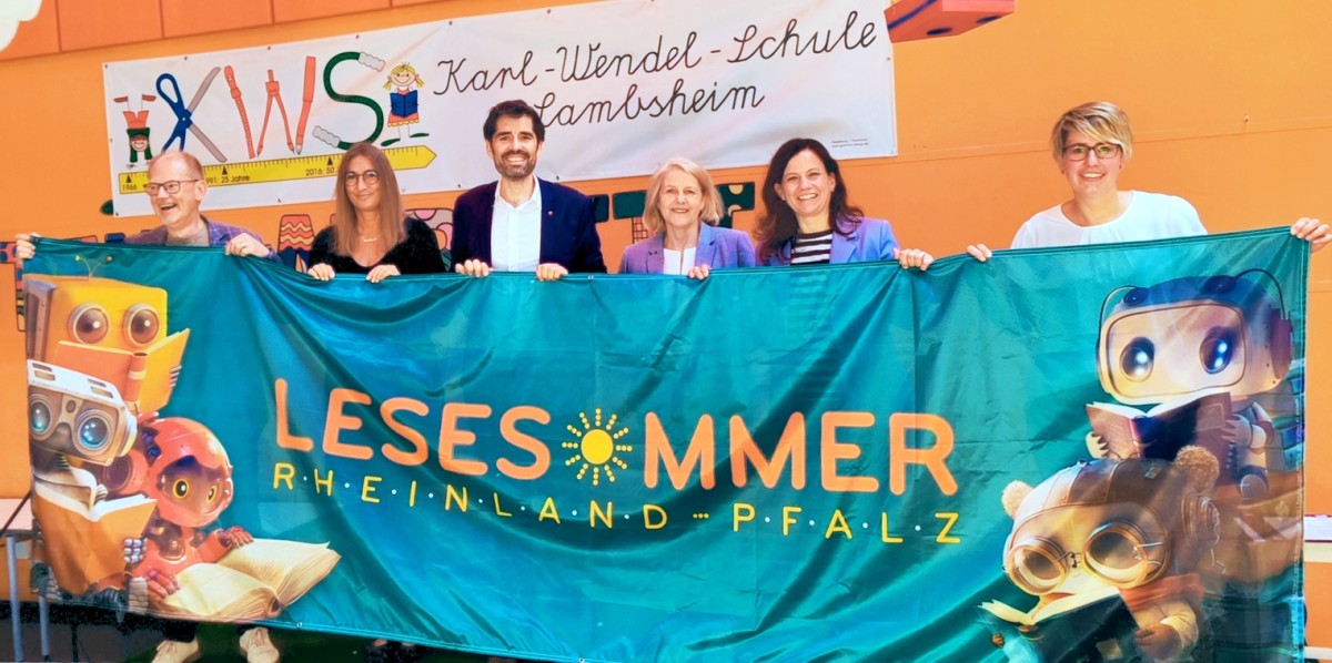 Er�ffnung des Lesesommers und Vorlese-Sommers 2026 in Lambsheim mit Kulturminister Sven Teuber (Bildmitte). V.l.n.r.: Hans-G�nther Scheer (Komm. Leiter LBZ), Anja Blum (Rektorin Karl-Wendel-Schule), Minister Sven Teuber (MKBWK), Marion Schneid (MDL, Stellv. Vorsitzende CDU-Fraktion, Barbara Eisenbarth-Wahl (B�rgermeisterin Lambsheim), Melanie Escheid (B�chereileiterin Lambsheim). Fotos: LBZ / Marie-Isabel Brauckhoff