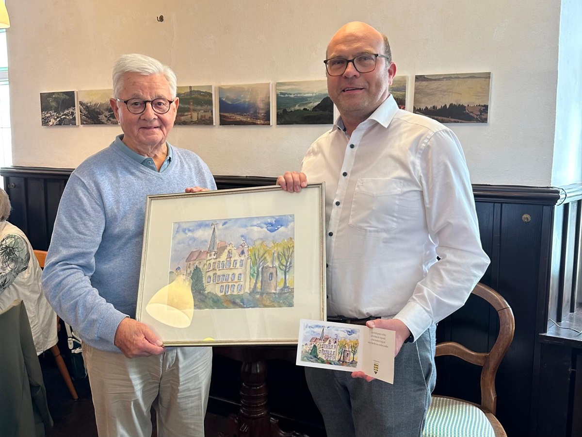 Ortsb�rgermeister Stefan Betzing stellte zusammen mit dem Maler der Burg Dattenberg, Hans-Joachim Schmitz, die neue Gl�ckwunschkarte der Ortsgemeinde Dattenberg den Besuchern der fairen Kaffeetafel vor. (Foto: Peter Gillrath)