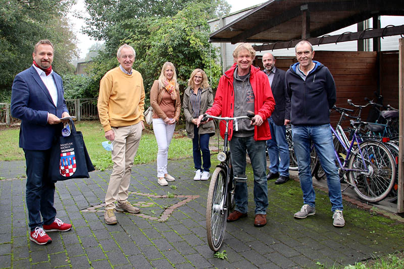 Vor der Fahrradwerkstatt, Am Spitzenbach 23, unter neuer Leitung von Reinhard Merklinger (mit Fahrrad)  v. l.: Erster Beigeordneter Holger Heuser, Helgi aufm Kampe, Jessika Voss (Fachdienst Soziales und Asyl), Nadine Batzella (Leiterin Fachdienst Soziales und Asyl), Reinhard Merklinger (neue ehrenamtliche Leitung), Felix Trimborn (Fachdienst Soziales und Asyl) und Reinhard Brix. Foto: Stadt Bad Honnef