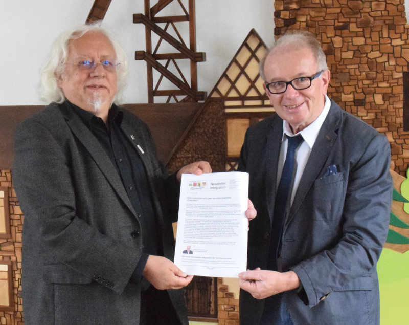 Integrationsbeauftragter Wolfgang Conzendorf (links) berreicht dem Beigeordneten der Verbandsgemeinde Flammersfeld, Rolf Schmidt-Markoski, ein Exemplar der ersten Newsletter Integration. Foto: VG Flammersfeld
