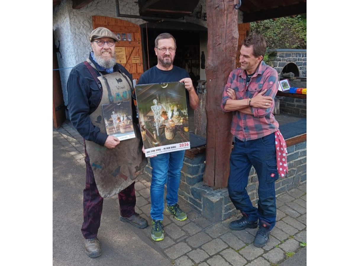 von links nach rechts: Metallknstler Winfried Gille, Fotograf Udo Runnebaum, Schmiedekollege Vaclav Turek schauen interessiert den neuen Kalender an. (Foto: Konrad Schwan.)