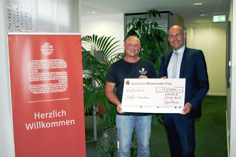 Sascha Eckhardt (r.), Leiter der Geschftsstelle Herdorf, berreicht Stefan Christian sinnbildlich einen Scheck ber 5.000 Euro. Foto: Sparkasse Westerwald-Sieg
