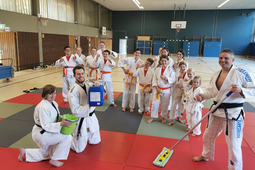 Schrubben nach dem Training, Vereinschef Dieter Nickol, rechts, mit dem Reinigungsgert nach dem Training; im Hintergrund sieht man die geffnete Hallentre zwecks Belftung (Foto: Judo- u. Ju-Jutsu - Verein Daaden)