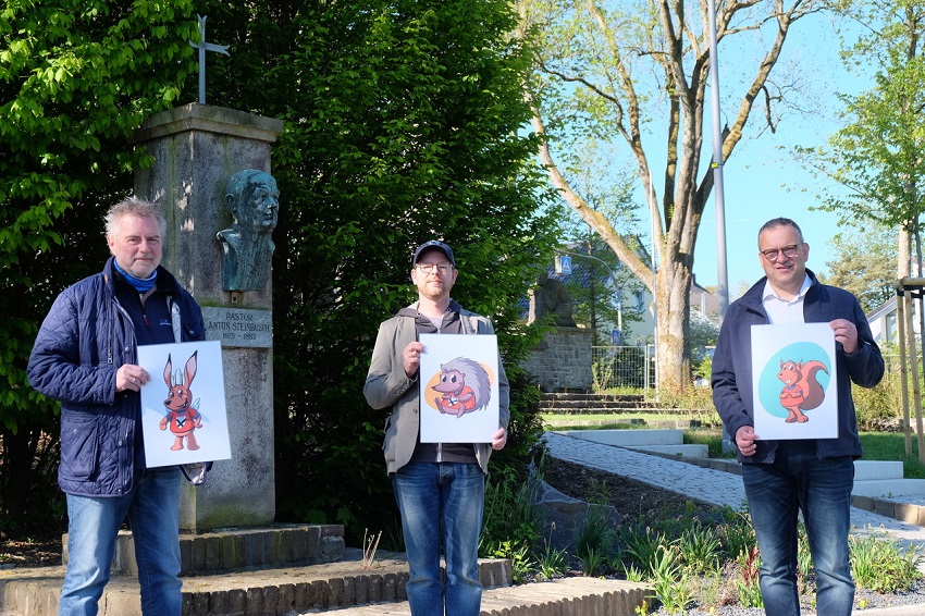 Welches der gezeigten Maskottchen soll es werden? v.l. nach r.: Joachim Schmidt (mit dem Dilldapp), Christian Kalkert (mit dem Igel) und Berno Neuhoff (mit dem Eichhrnchen) in der fast fertig gestalteten Steinbuschanlage. (Foto: KathaBe)