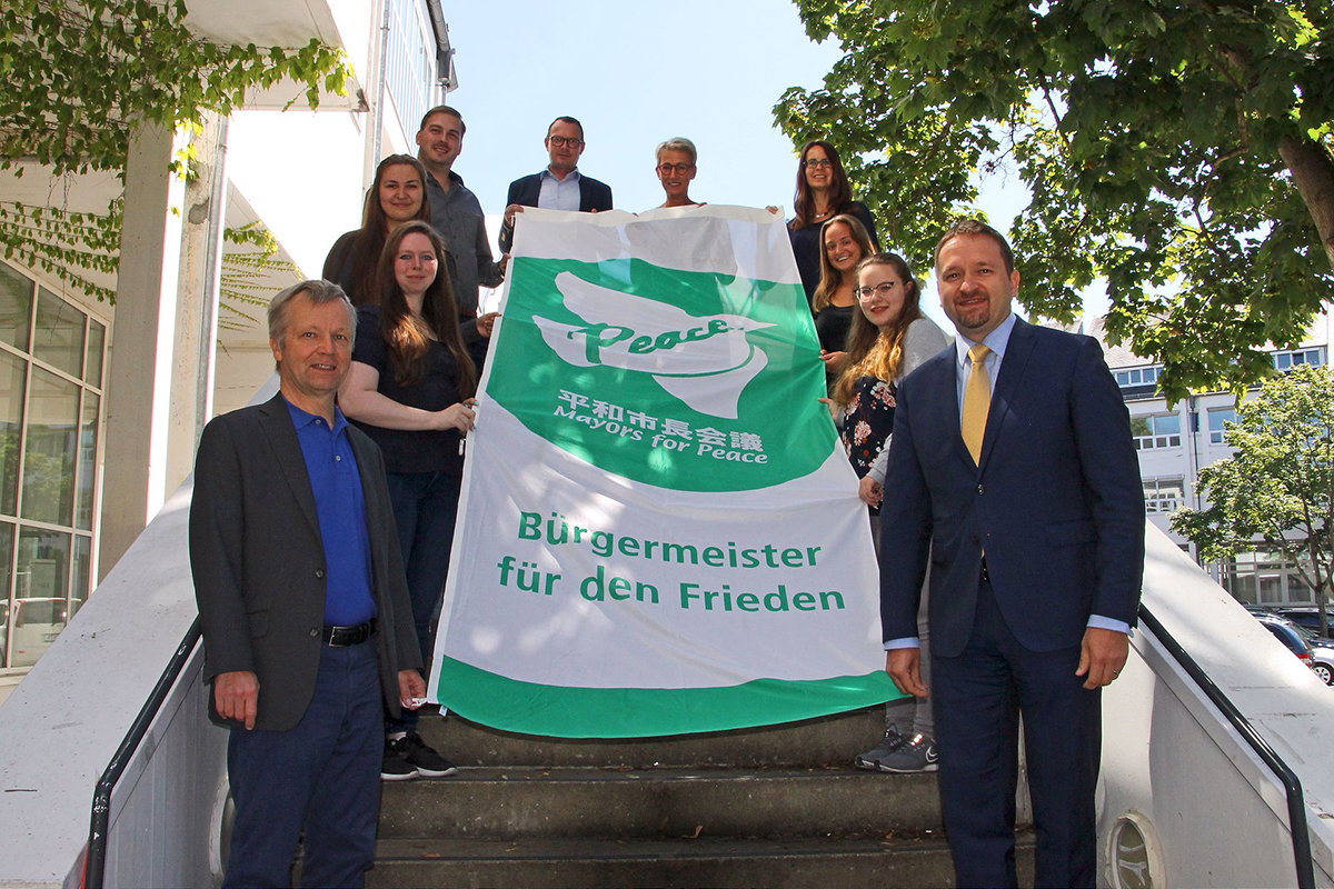 Mitarbeitende und Auszubildende der Stadt Bad Honnef mit Brgermeister Otto Neuhoff (links) und Erstem Beigeordneten Holger Heuser (rechts) untersttzen die Ziele der Mayors for Peace fr atomare Abrstung und halten die Mayors-for-Peace-Flagge. Foto: Stadt Bad Honnef