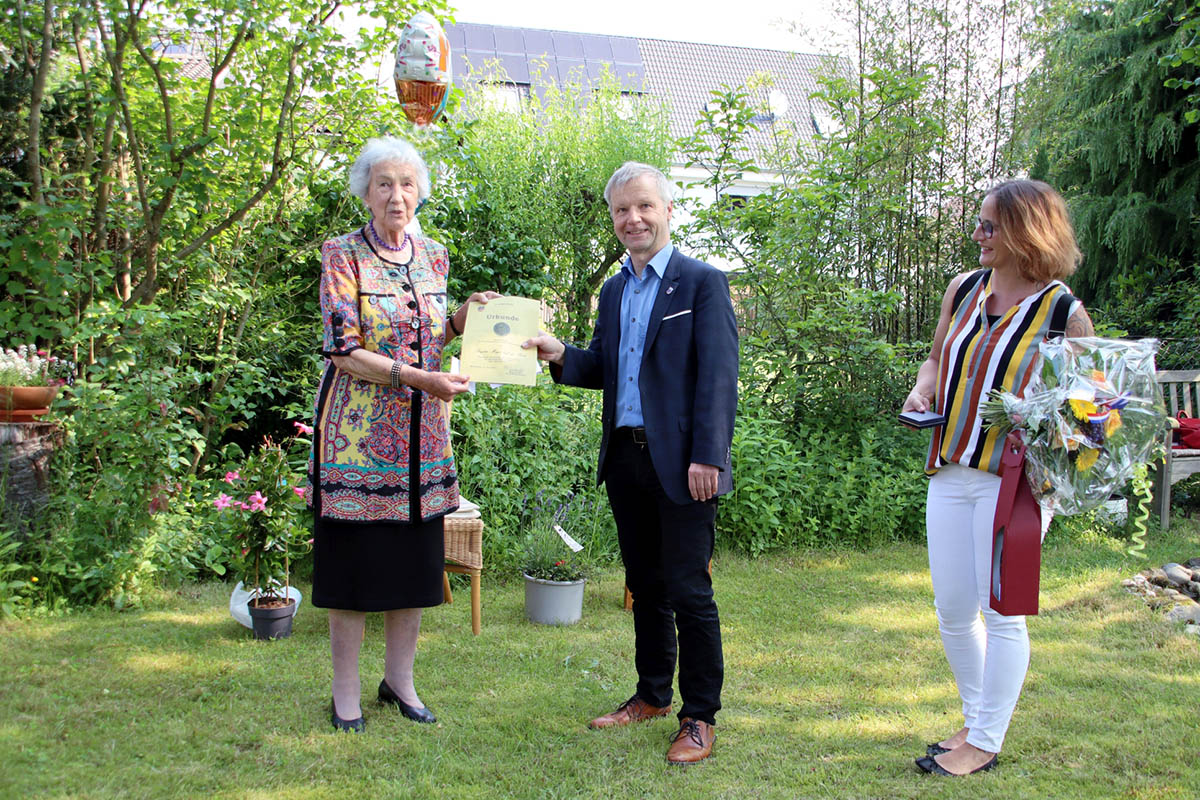 Im schnen Garten von Brigitte Meyer auf der Heide:  Brgermeister Otto Neuhoff berreichte Brigitte Meyer auf der Heide (links) Dankmedaille und Urkunde zum Dank fr ehrenamtliches Engagement und Nadine Batzella (Fachdienstleiterin Soziales und Asyl) (rechts) gratulierte ihr zur Auszeichnung. Foto: Stadt Bad Honnef