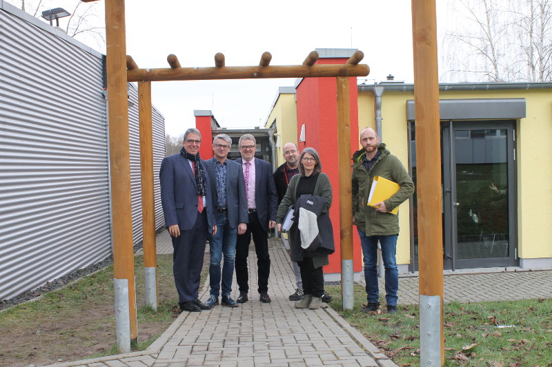 Die Projektbeteiligten sind von der Planung berzeugt: Die Mensa an der Heinrich-Roth-Realschule plus (hinten rechts) wird erweitert auf die Flche, wo derzeit noch ein mit Alu-Blechen verkleideter Klassenraum-Container steht (links). Foto: Privat