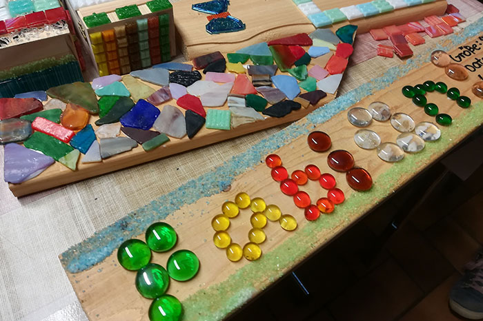 Dieses Mal verzieren die Kinder unterschiedliche Objekte mit bunten Mosaiksteinen und Glasnuggets. Foto: Stadt Neuwied
