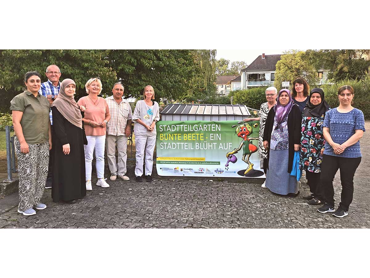 Grtner des Stadtteilgarten-Projekts prsentieren gemeinsam mit Quartiermanagerin Alexandra Heinz (4. von links), Diakonie-Geschftsfhrerin Renate Schning (6. von links) und Diakonie-Mitarbeiterin Elke Voss (3. von rechts) stolz das neue Banner. (Foto: Stadt Neuwied)