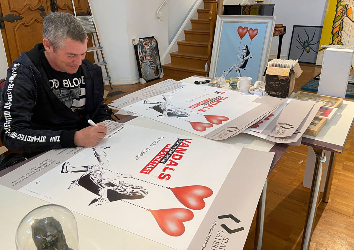 Whrend eines Besuchs in der Stadtgalerie Mennonitenkirche signiert JPS einige Ausstellungsplakate, die sein "Dont Look Back in Anger" zeigen. (Foto: Stadt Neuwied / Melanie Lange)