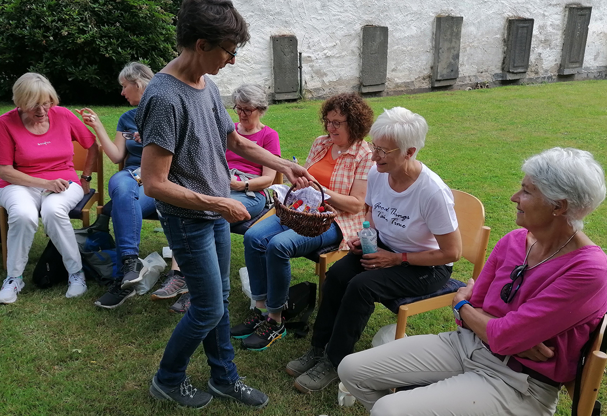 Bei einer Pause im Garten der Evangelischen Kirchengemeinde in Altwied berreicht Heidi Hahnemann den Ehrenamtlichen ein kleines Geschenk. (Foto: Hospizverein)