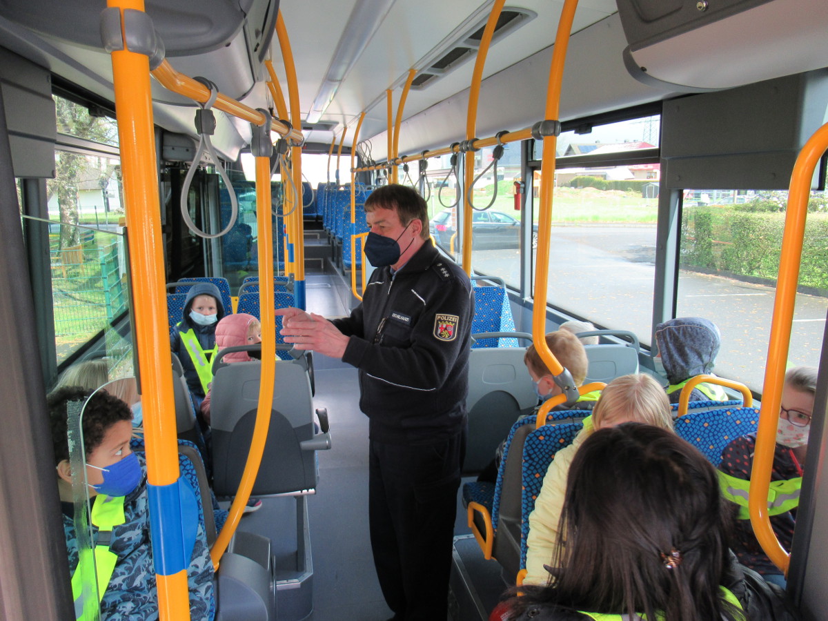 Whrend der Busfahrt zeigt Polizist Werner Eichelhardt, wie man richtig und sicher sitzt. (Foto: Kita Pracht)
