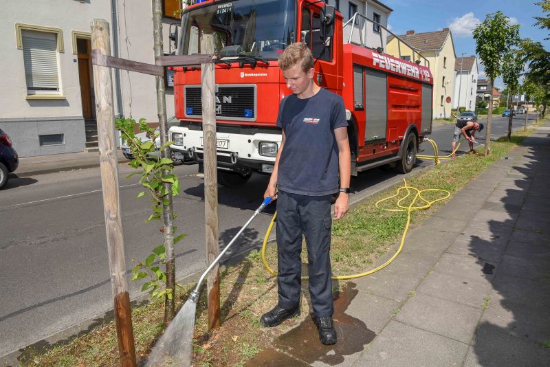 Starke Untersttzung durch die Floriansjnger: Philipp Benner und Achim Schneider (hinten) von der Feuerwehr Neuwied helfen beim Gieen die Bume. Das muss behutsam gemacht werden, da die Oberflche extrem trocken und hart ist. Foto: SBN