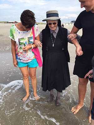 Sr. Placidia (89) ist zu ersten Mal in ihrem Leben am Meer: Die Mitarbeiter Rita Thomas und Michael Mauer fhren die zierliche Ordensschwester mit Strmpfen ins khle Nass. Foto: pr