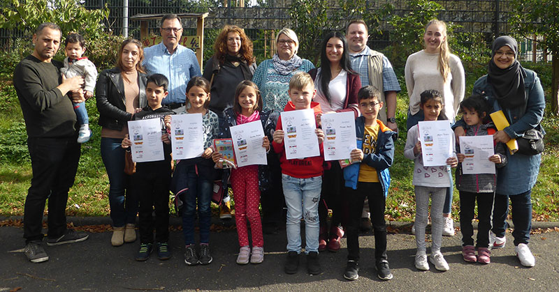 Sprachfrderkraft Lisa Zinndorf (2. von rechts), die Leitungen der katholischen Kita St. Matthias, Thomas Blsche (3. von rechts), und des Herrnhuter Kinderhauses, Pamela Brings (4. von rechts), sowie Mitarbeiter der Abteilung Kindertagessttten und Kindertagespflege, Fachbereichsleiter Karl Oster (3. von links) und Petra Marks (4. von links), gemeinsam mit Kindern und Eltern. Foto: Stadt Neuwied. 