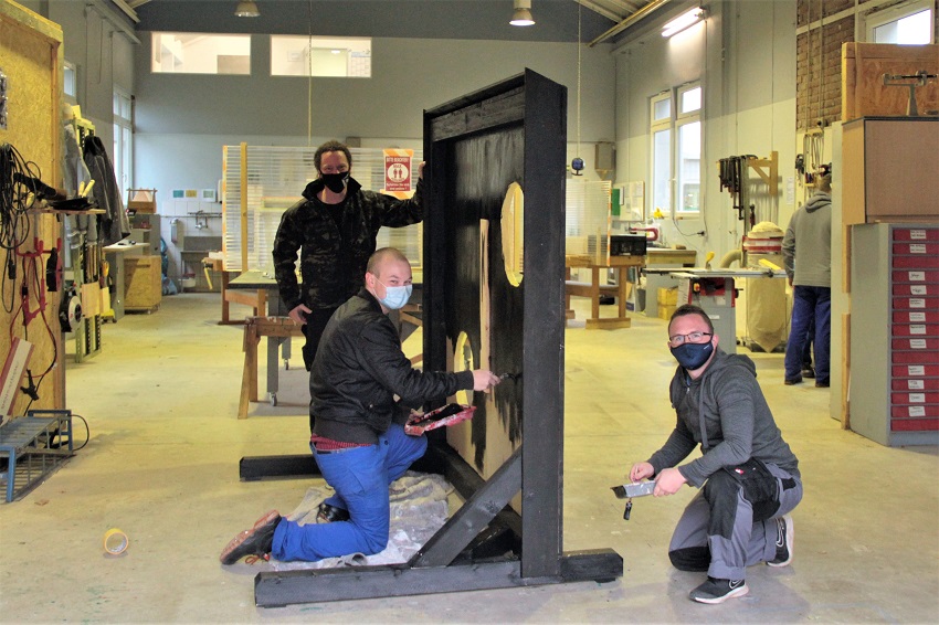 Eine Torwand mit Symbolkraft: Projektbezogene Arbeit nennt Anleiter Bodo Richter (im Hintergrund) das, was die Mnner und Frauen in der Werkstatt in der Walzwerkstrae in Wissen fr bessere Zeiten ohne Maske und Corona-Einschrnkungen gefertigt haben. Denn  im Projekt Spurwechsel ist es wie mit der Torwand: Erst hinter dem Nadelhr tun sich Perspektiven auf. (Foto: neue arbeit e.V.)
