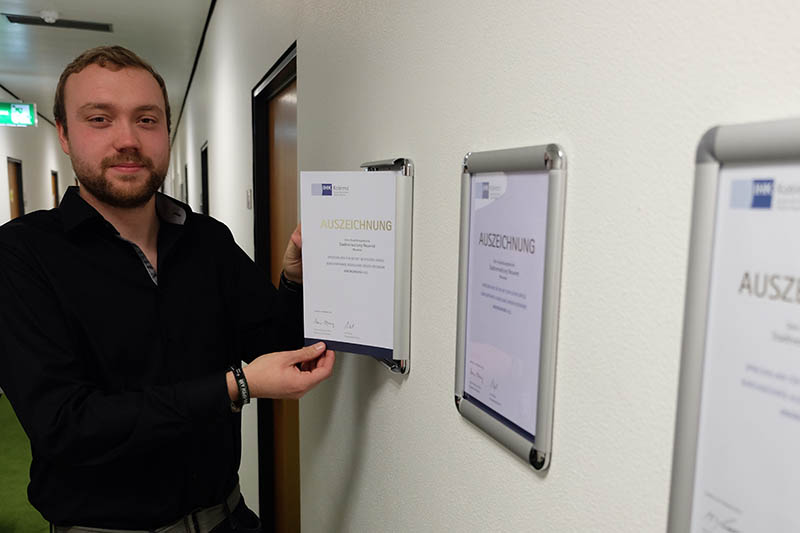 Tim Betz bringt die Urkunde an, mit der die IHK die Stadtverwaltung als Ausbildungsbetrieb ausgezeichnet hat. Foto: Stadt Neuwied