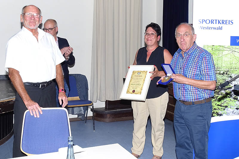 Die Ehrenplakette des Fuballkreises Westerwald/Sieg an den scheidenden Sportkreisvorsitzenden Albrecht Gehlbach (links) berreichten Susanne Bayer (Mitte) und Willi Simon (rechts). Im Hintergrund der designierte neue Vorsitzende des Sportkreises Westerwald, Olaf Rttig. Foto: Willi Simon