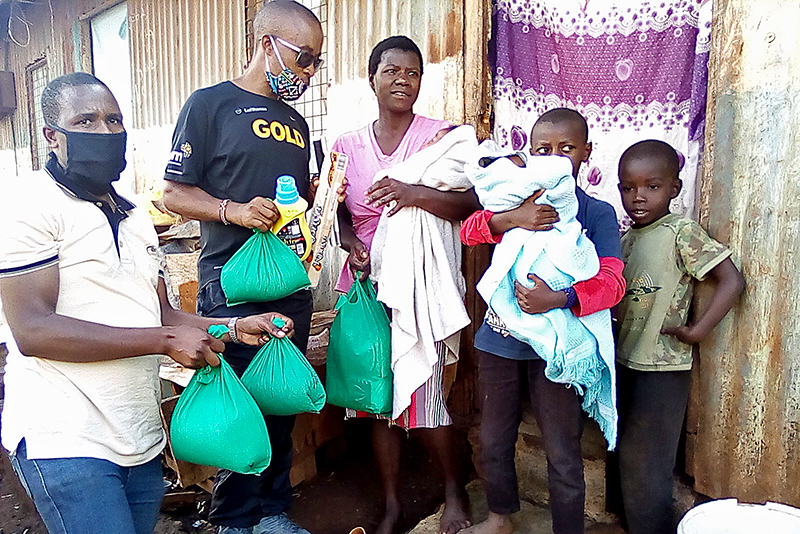 Das Foto zeigt Henry Wanyoike (Zweiter von links) bei der bergabe von Lebensmittelspenden in Kenia. Foto: privat