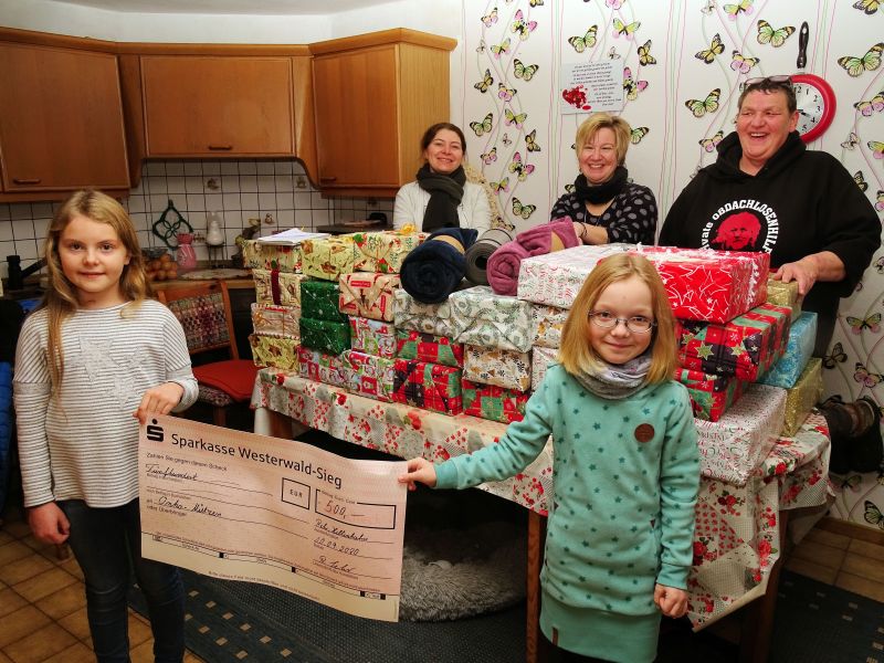 Mehr als 100 Hilfepckchen, hier ein Teil davon, schnrten (v.r.) Petra Schmidt-Scheld, Manuela Simon-Kurzhals und Rebecca Pfeifer. Sie fllten dazu auch Kleiderscke mit Wintersachen. Eileen (links) und Franziska-Maria halfen mit beim Pckchen packen und prsentieren einen Spendenscheck. Foto: Willi Simon 