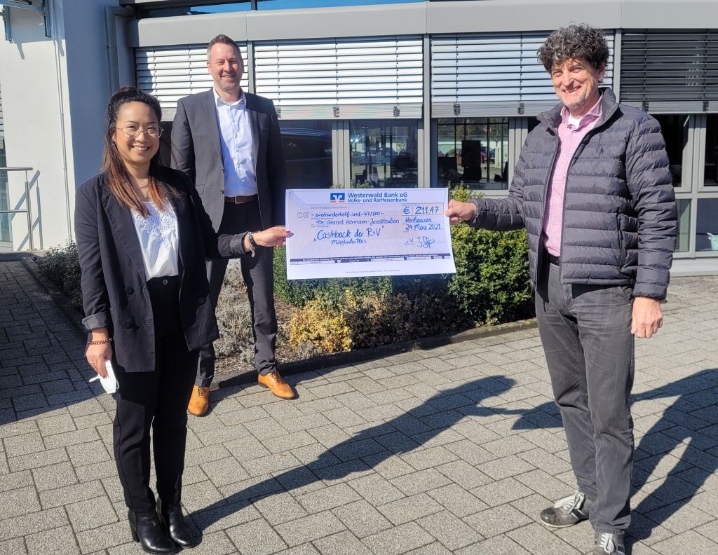 Thuy Trang Dang, Auendienstmitarbeiterin der R+V und Heiko Zelmer, Geschftsstellenleiter Filiale Horhausen bergeben, stellvertretend fr alle Mitglieder der Westerwald Bank, einen Cashback-Scheck an das Mitglied Dr. Gernot Heuen. Foto: Westerwaldbank