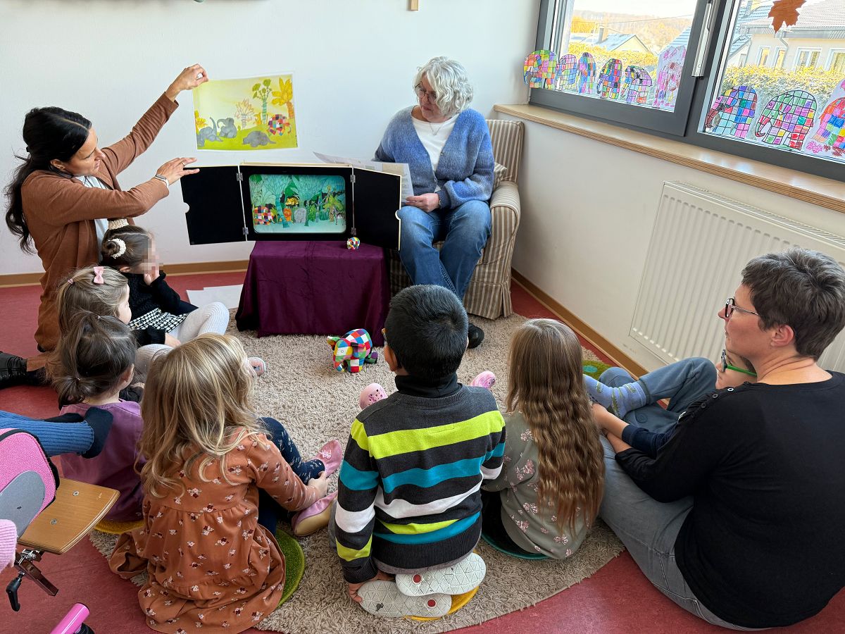 Bunter Vorlesespa� in Wirges: Andrea Berger (rechts) las den Kindern der Caritas-Kita Sankt Franziskus die Geschichte vom Elefanten Elmar vor. Unterst�tzt wurde sie dabei von Anke Meurer (links), die die Erz�hlung mit Bildern im Kamishibai-Erz�hltheater begleitete. (Foto: Holger P�ritzsch/Caritasverband WWRL)