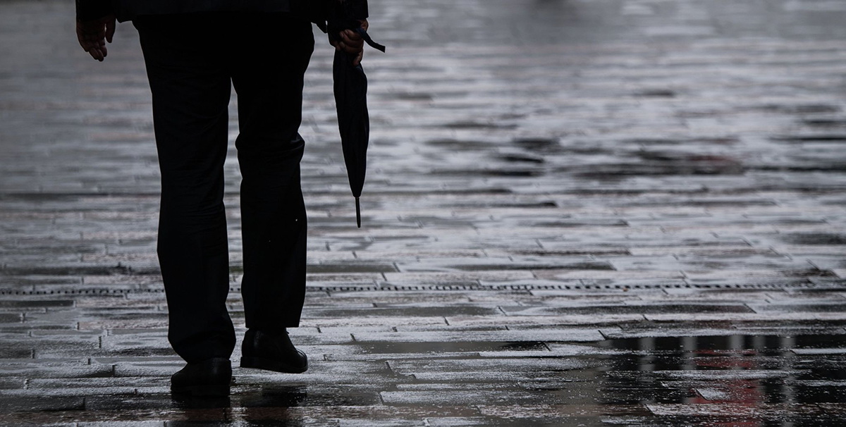Ein Passant geht mit Regenschirm in der Hand durch Mainz. Foto: Andreas Arnold/dpa