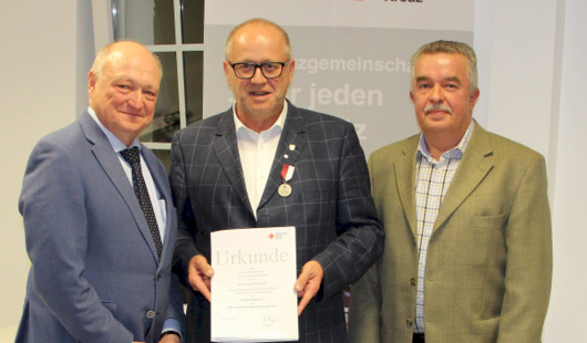 Landrat Michael Lieber (links) als Prsident des hiesigen DRK-Kreisverbandes und Kreisgeschftsfhrer Alfons Lang (rechts) bergaben Enders die DRK-Verdienstmedaille. (Foto: DRK)