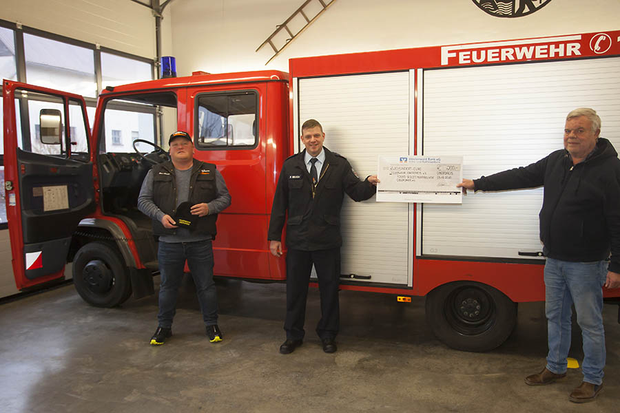 Marc Abresch (links) und Frank Kstner (rechts) berreichen Wehrfhrer Peter Reusch Mtzen und Scheck. Foto: Feuerwehr VG Puderbach