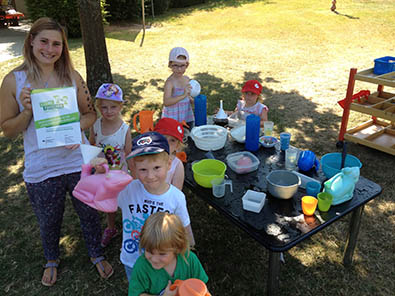 Erzieherin Lea Klein mit den Kindern Merle, Greta, Josi, Paul, Victoria und Isabella, die sich freuen Forscherkids zu sein. Besonders das Experimentieren mit Wasser macht bei diesen Temperaturen besonders Spa. Foto: KVHS