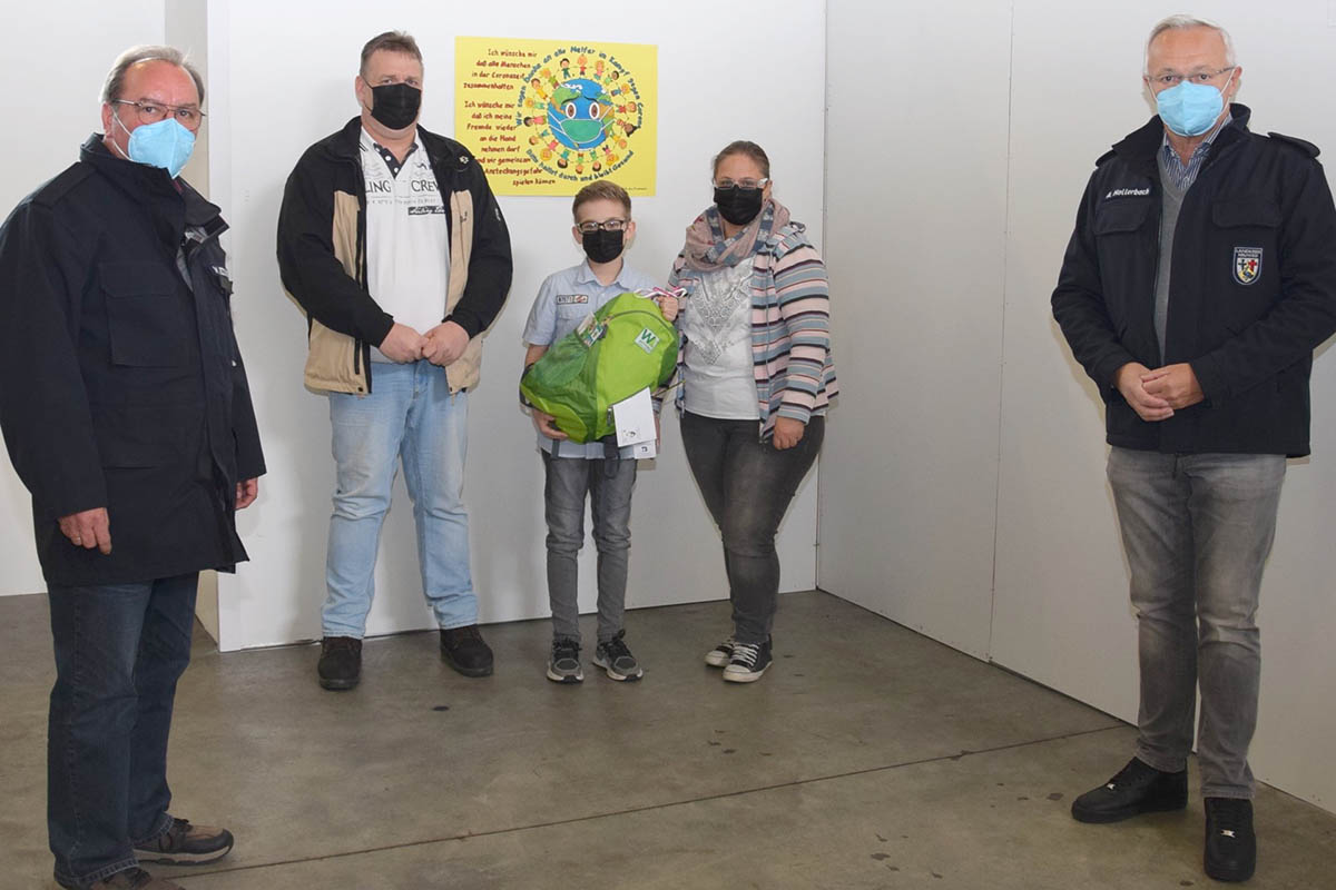 Mit dem Sonderpreis der Jury wrdigten Landrat Achim Hallerbach (ganz rechts im Bild) und Impfkoordinator Werner Bcking (ganz links) das Plakat von Alessio Pothoff, das zuknftig den Eingangsbereich im Impfzentrum zieren wird. Foto: Kreisverwaltung