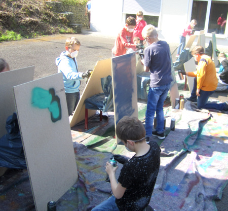 Mit Mund- und Nasenschutz ausgestattet sowie mit Sprhdosen in der Hand durften die Viertklssler der Grundschule Etzbach ihre ersten Graffitis auf Holzplatten sprhen. (Foto: Grundschule Etzbach)