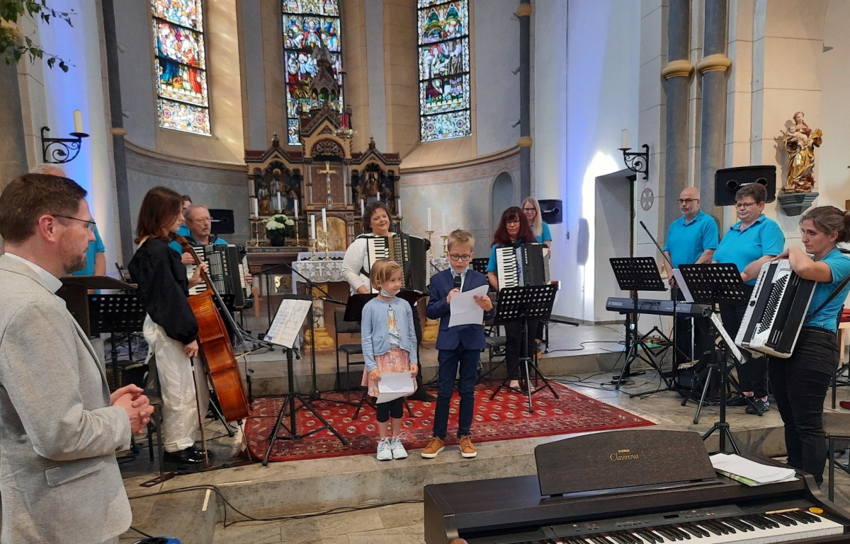 Mit einem Friedensgebet erffneten die Kinder Mirijam und Lukas Schmidt das Programm. Links: Pastor Peter Strauch, der das Konzert moderierte. Auf dem Foto ist auch das Akkordeonorchester Bonefeld zu sehen, dass schon nach den ersten Takten die Herzen des Publikums erobert hatte. (Fotos: Veranstalter)