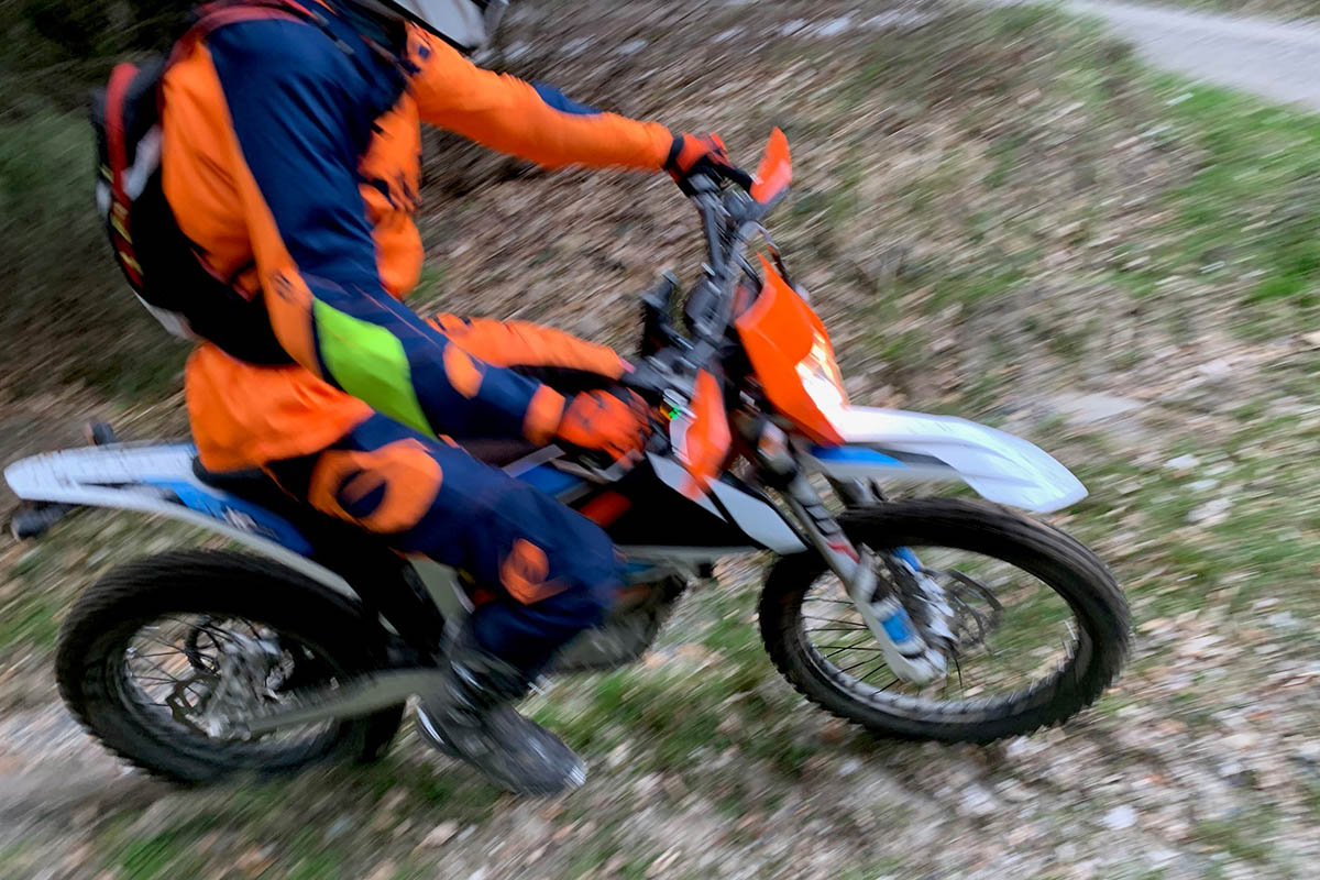 Ein unbekannter Motorradfahrer mit orangefarbenem Oberteil im Wald; © Polizei RLP