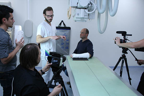 Das Foto entstand bei den Dreharbeiten des Films, der eigens ber die Ausbildung der MTRAs gedreht wurde und unter www.rheinisches-bildungszentrum.de/filme/ aufgerufen werden kann: Der frisch examinierte MTRA Juri Tchoumakov (2. von rechts) bereitet das Rntgen des eigens fr den Film eingegipsten Arms von Oberarzt Dr. Stefan Lohmaier vor. Fotonachweis: Andrea Schulze