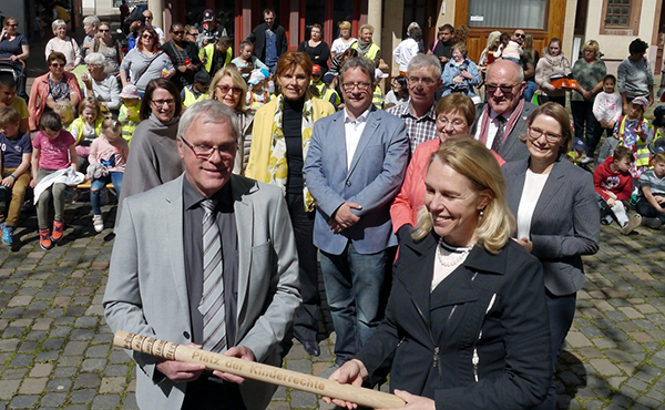 So langsam wird es schon eng auf dem Staffelholz, das Hhr-Grenzhausen zur Einweihung des ersten Platzes der Kinderrechte auf die Reise geschickt hat. Stadtbrgermeister Michael Thiesen bergab es der Oberbrgermeisterin von Bad Kreuznach, Heike Kaster-Meurer. Mit dabei (zweite Reihe von rechts): Bildungsministerin Stefanie Hubig, DKSB-Prsident Heinz Hilgers und die Vorsitzende des  Kreisverbandes Westerwald/Ortsverband Hhr-Grenzhausen, Heidi Ramb. Foto: PR