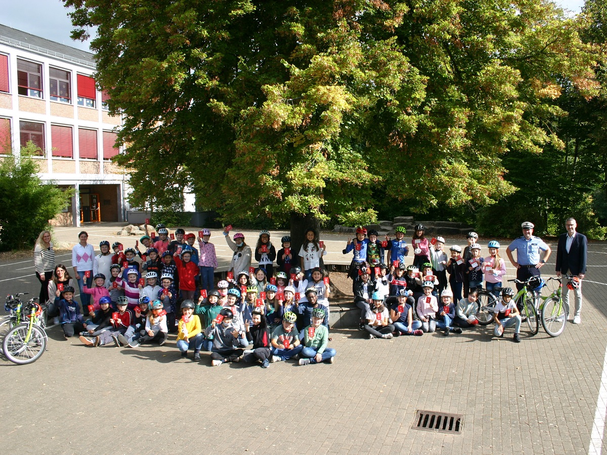 Schulleiterin Sandra Mller (l.), die Kinder der Klassen 4a, 4b (Leitung Bianca Georg, 2.v.l.) und 4c (Leitung Pia Burth, 4.v.l.), Polizeihauptkommissar Volker Frink (2.v.r.) und Peter Mohr (r.) (Fotoquelle: Sparkasse Westerwald-Sieg)