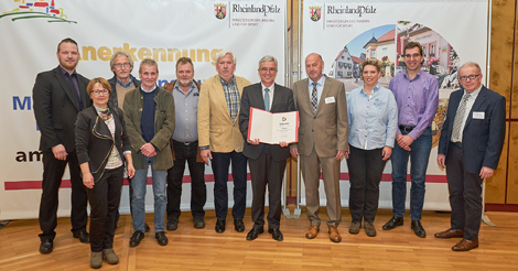 Das Foto zeigt den Innenminister (Bildmitte) neben Ortsbrgermeister Richard Schmitt im Kreise der Vertreter des Ortsgemeinderates. Dorfmoderatorin Christiane Hicking (links) und der Erste Beigeordnete der Verbandsgemeinde Flammersfeld, Rolf Schmidt-Markoski (rechts), gratulierten der Gemeinde zur Anerkennung. Foto: pr