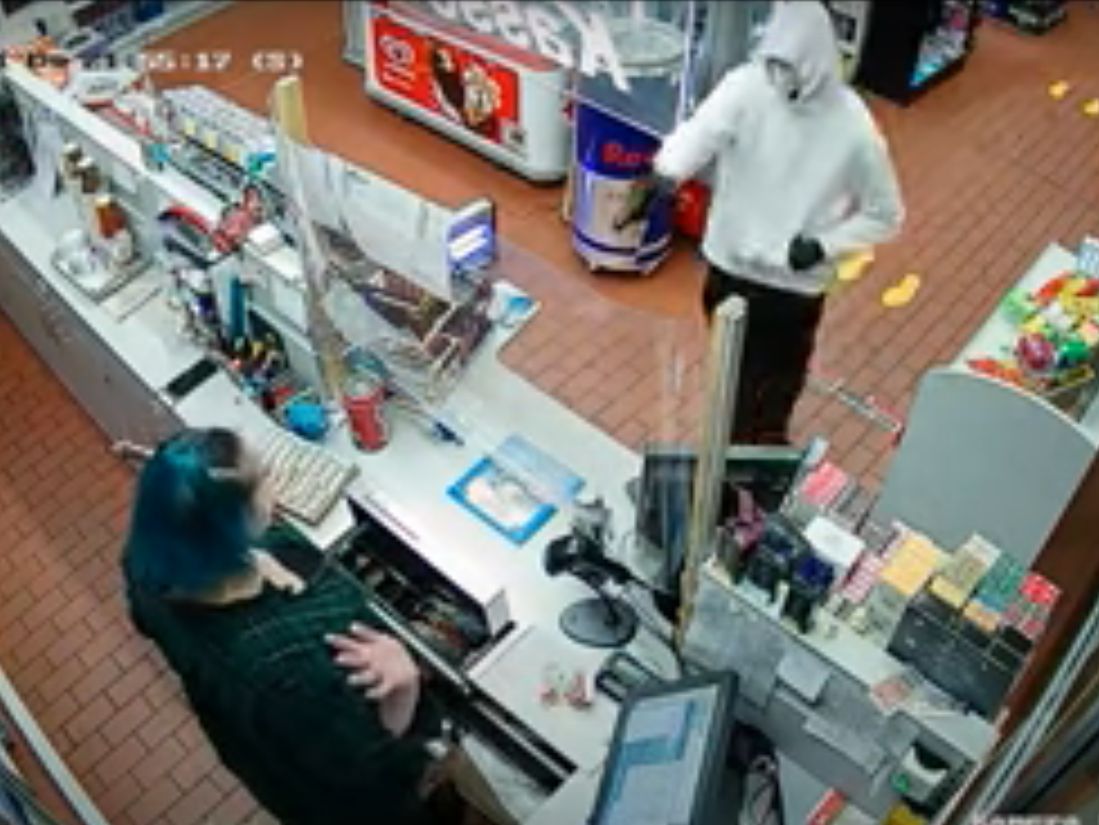 Die Videoaufnahme zeigt, wie der noch Unbekannte die Tankstellen-Mitarbeiterin mit einer Pistole bedroht - woraufhin sie seiner Forderung nachkam und ihm Bargeld aushndigt. (Screenshot: Video Polizei Rheinland-Pfalz)