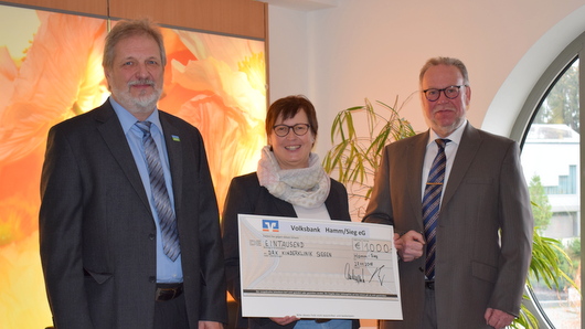 Die Vorstnde der Volksbank Hamm, Dieter Schouren (rechts) und Uwe Lindenptz (links), berreichen den symbolischen Scheck an Bettina Kowatsch von der DRK-Kinderklinik Siegen. (Foto: Volksbank Hamm)