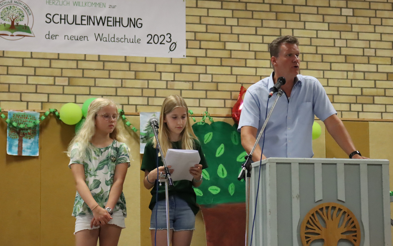Schulleiter Stefan Gleis und die Schlerinnen Charlotte und Lia begrten die Gste in der voll besetzten Turnhalle und berichteten abwechselnd, wie sie die Bauzeit fr das neue Schulgebude erlebt haben. (Foto: VG Montabaur / Christina Wei)