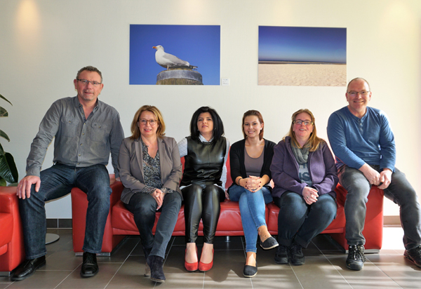 Krankenhaus-Mitarbeiter, deren Fotos in der Ausstellung zu sehen sind, mit zwei Urlaubsmotiven im Hintergrund. Foto: Privat